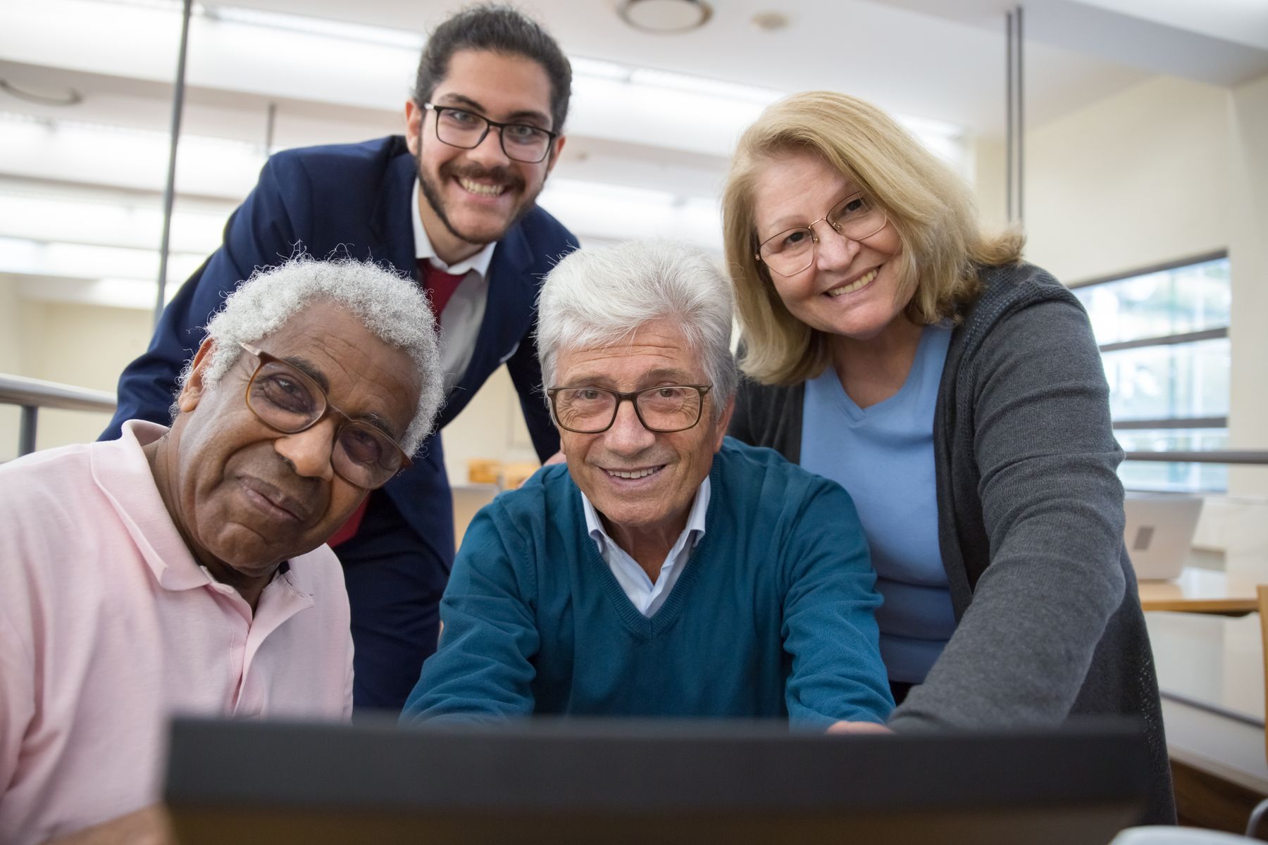 A diverse group of older adults and a younger companion smiling together